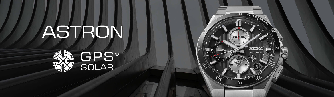 Relógio prateado de mostrador preto com fundo escuro de um edifício, para a categoria seiko astron.